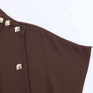 Detail of dark brown blouse featuring stand collar and textured gold lava buttons