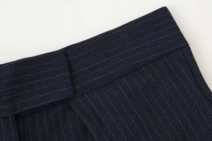 Detail of navy blue pinstripe wide leg trousers showing waist structure and twill fabric