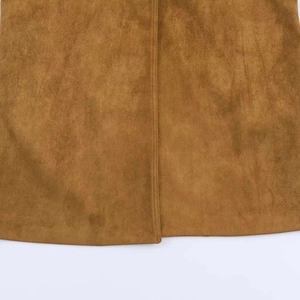 Dettaglio della trama in camoscio marrone e delle cuciture fini sull'orlo del cappotto