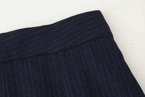 Detailed close-up of dark blue pinstripe wide-leg trousers showing refined waist stitching