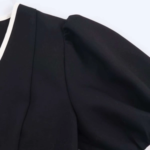 Détail de la robe noire avec liseré blanc contrastant et manches bouffantes élégantes