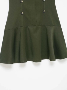 Detail of dark green dress showing double-breasted buttons and ruffled hemline texture