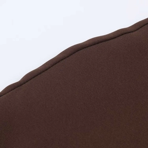 Detail view of dark brown woven fabric texture with precise rolled edge stitching