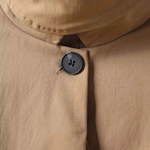 Makroansicht des khakifarbenen Parka-Ausschnitts mit schwarzem Knopf und Twill-Baumwolle