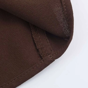 Detail of dark brown heavy woven fabric with neat double-stitched hem on a summer dress