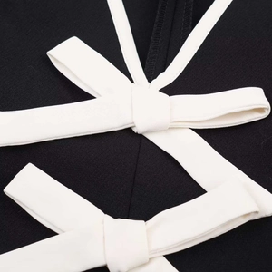 Détail de la robe noire avec nœud croisé blanc et texture de tissu finement nervuré