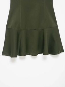 Detailed close-up of dark green ruffled hem with refined stitching and woven fabric