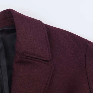 Close-up of burgundy wool blend overcoat featuring notched lapels and tidy stitching detail