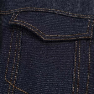 Vue détaillée du tissu denim bleu foncé avec des surpiqûres ambrées et un rabat de poche