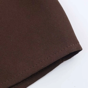 Detailed close-up of dark brown fabric showing precise stitching and woven texture