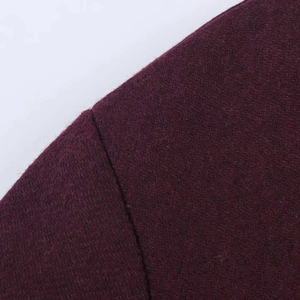 Macro shot of sleeve seam on a deep burgundy wool coat showing fine fabric texture