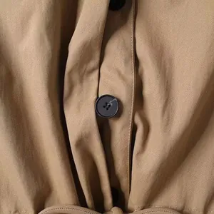 Detailansicht der khakifarbenen Köperstruktur mit schwarzen Knöpfen und Taillengürtel