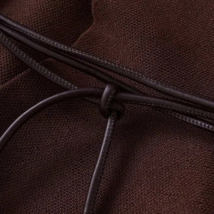 Détail de maille marron foncé avec un cordon de serrage fin en cuir et texture douce