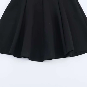 Détail de l'ourlet plissé d'une mini-robe noire montrant la texture et la couture du tissu