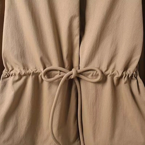 Detail der verstellbaren Kordelzug-Taille und der Webstruktur am khakifarbenen Parka
