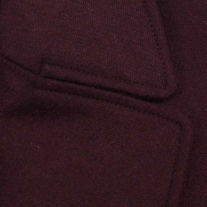 Detailed macro view of the premium burgundy wool fabric texture and pocket stitching
