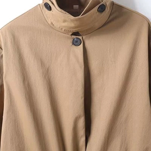 Detail der khakifarbene Stehkragenjacke mit schwarzen Knöpfen und Baumwollstruktur
