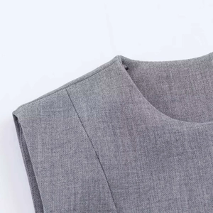 Detail of the grey sleeveless dress showing the crew neck design and woven suit fabric texture