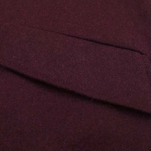Close-up of wine red wool coat fabric showing premium texture and neat pocket stitching