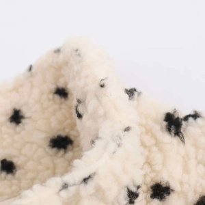 Close-up of soft beige fleece fabric featuring a stylish black polka dot pattern