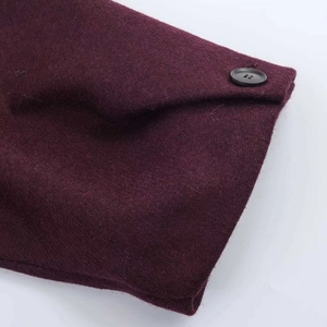 Close-up of wine red wool coat detail featuring thick texture and a black four-hole button
