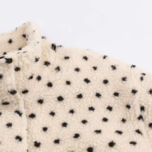 Close-up of cream fleece jacket featuring a high collar and black polka dot pattern