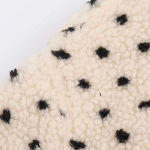 Detailed macro view of the thick sherpa fleece fabric texture with black polka dot pattern