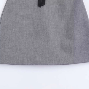 Detail view of a grey dress with a black grosgrain bow accent on the waistline