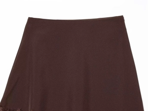 Detail of a chocolate brown mini skirt featuring a flat waistband and delicate lace trim
