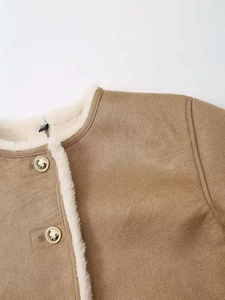 Gros plan détaillé d'une veste en daim camel avec bordure en peau lainée blanche et boutons dorés