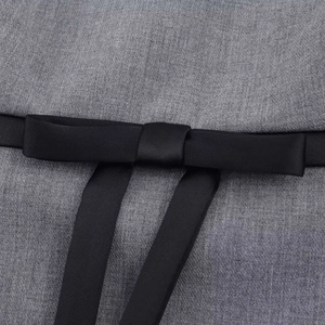 Detail of grey dress waistline with elegant black satin bow belt and textured fabric