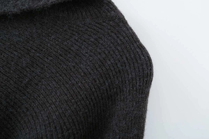 Macro shot of charcoal grey knit poncho top collar and shoulder seam craftsmanship