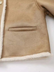 Détail d'une veste en daim camel avec bordure en similicuir mouton blanc et poche