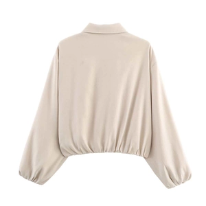 Rear view of a beige cropped jacket showing loose drop-shoulder cut and elastic cuffs