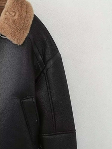 Détail d'une veste en cuir noir avec col en fausse fourrure marron et logo embossé