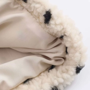 Macro detail of plush white polka dot fleece jacket with warm inner lining fabric