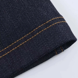 Vue détaillée de la double couture jaune sur un tissu en denim bleu foncé de qualité