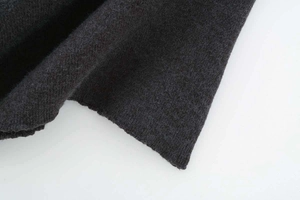 Macro view showing the tight knit texture and soft charcoal grey wool fabric of the sweater