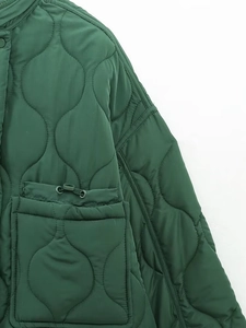Detail of dark green quilted jacket featuring wave stitching and adjustable drawstring pockets