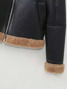 Détail d'une veste en similicuir noir avec doublure en peau de mouton brune et zip argenté