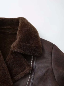 Detail of dark brown faux shearling collar and suede texture on short jacket