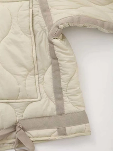 Detail of light beige quilted jacket with gourd patterns and adjustable drawstring hem