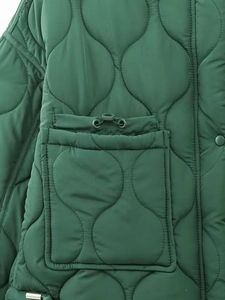 Detail of dark green quilted jacket featuring onion pattern stitching and drawstring pocket