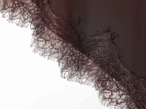 Detailed macro view of delicate eyelash lace trim on smooth dark brown satin fabric