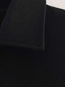 Close-up of black twill jacket collar showing precise stitching and premium fabric texture