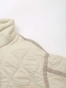 Macro detail of quilted jacket featuring onion stitching and contrast taupe piping trim