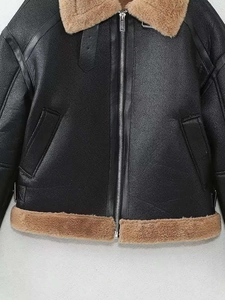 Détail de la veste de motard vintage en similicuir noir et bordure en peau lainée brune