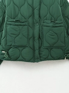 Detail of dark green quilted jacket featuring onion stitch pattern and drawstring pockets