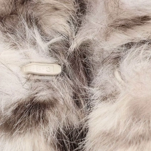 Close-up of winter faux fur coat with animal print texture and beige plastic buckle detail