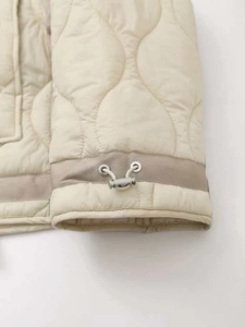 Detail of wavy quilted puffer jacket featuring adjustable silver buckles and white drawstrings